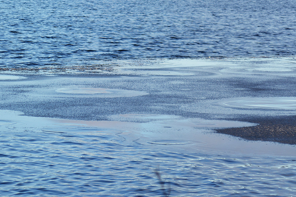 Lähikuvaa järven pinnasta, jonka peittää osittain ohut jääkerros.